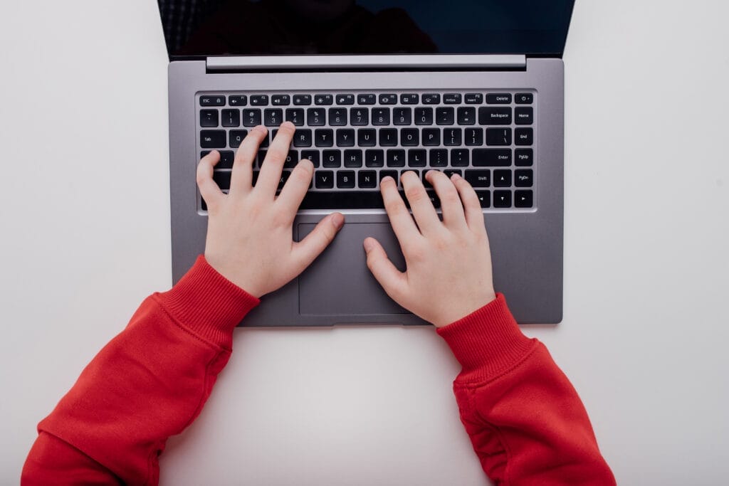 Why Parents Aren’t to Blame for Roblox’s Safety Failures close up, Child's hand on a laptop keyboard.